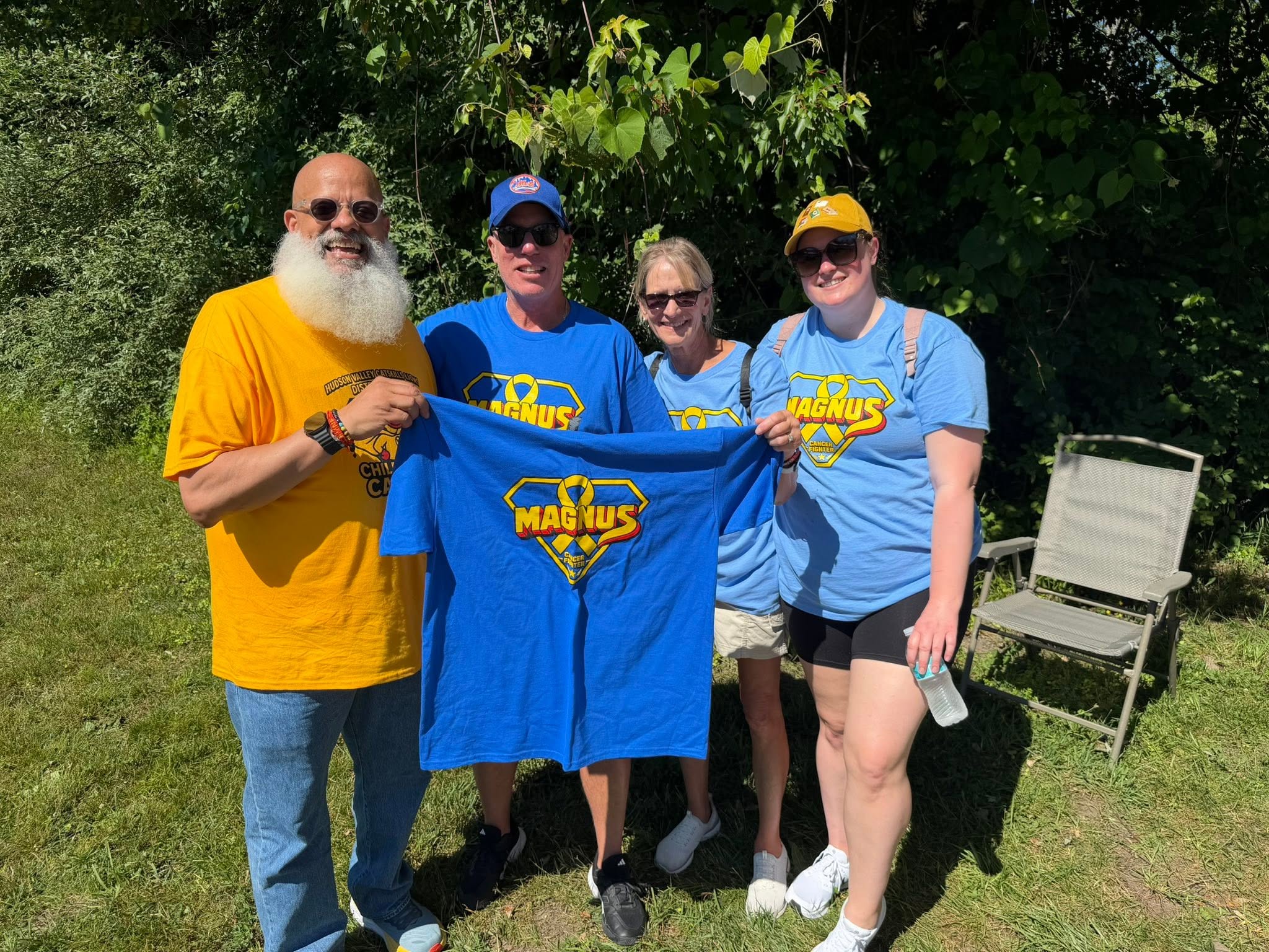 Four people holding up blue Magnus t-shirts